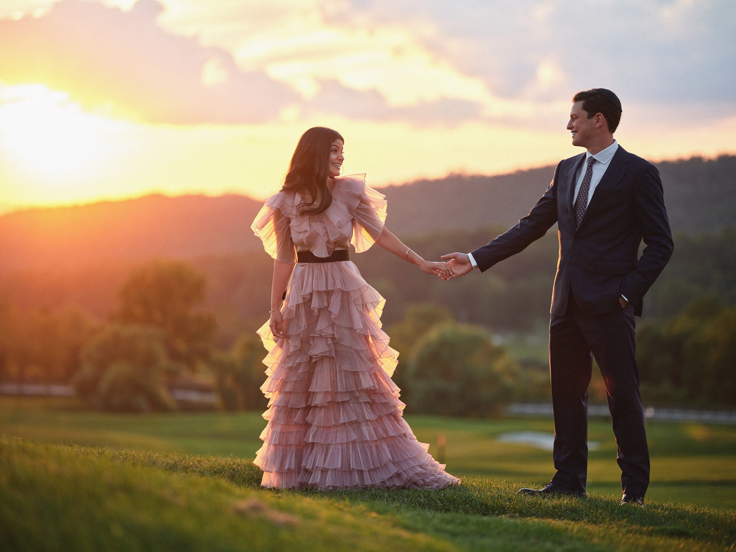 Bride wearing a pink wedding dress with groom on a golf course at sunset