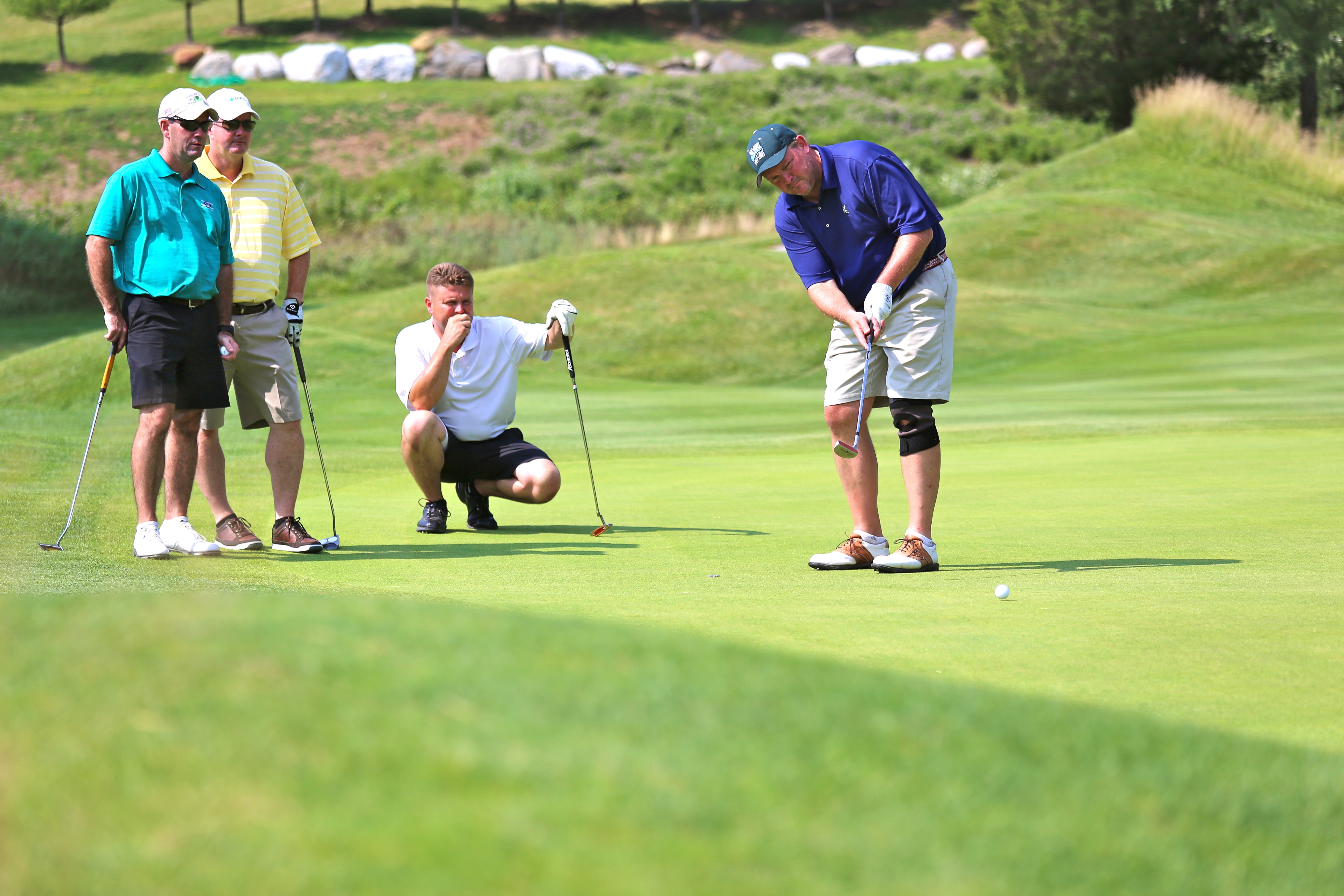 A foursome of guys on the putting green of a golf course at Crystal Springs Resort