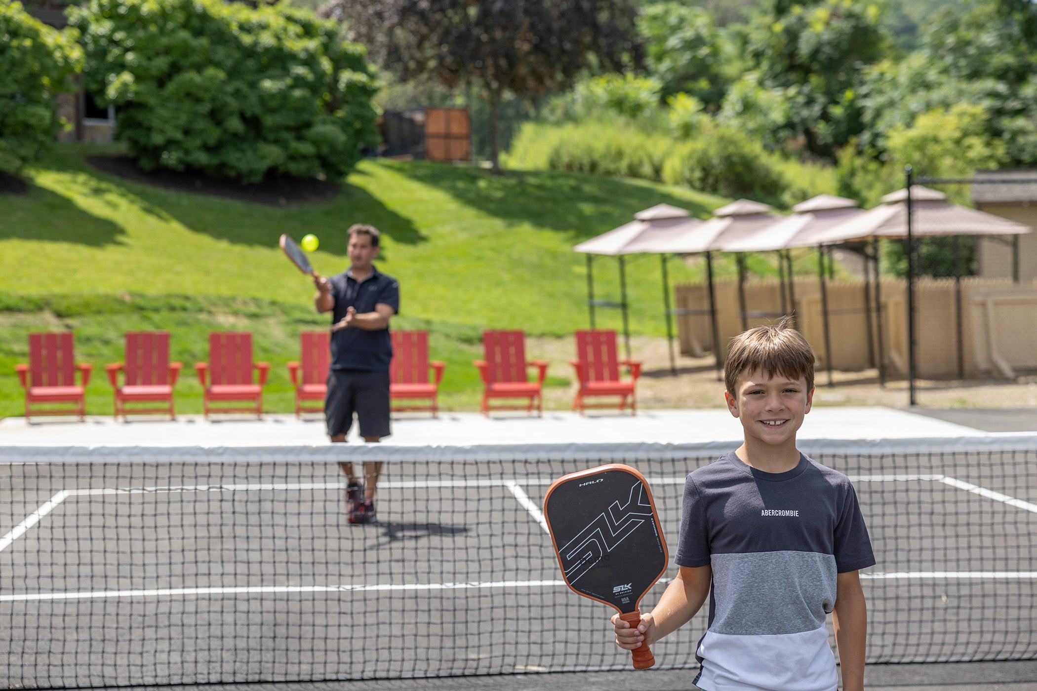Boy and father playing pickleball.