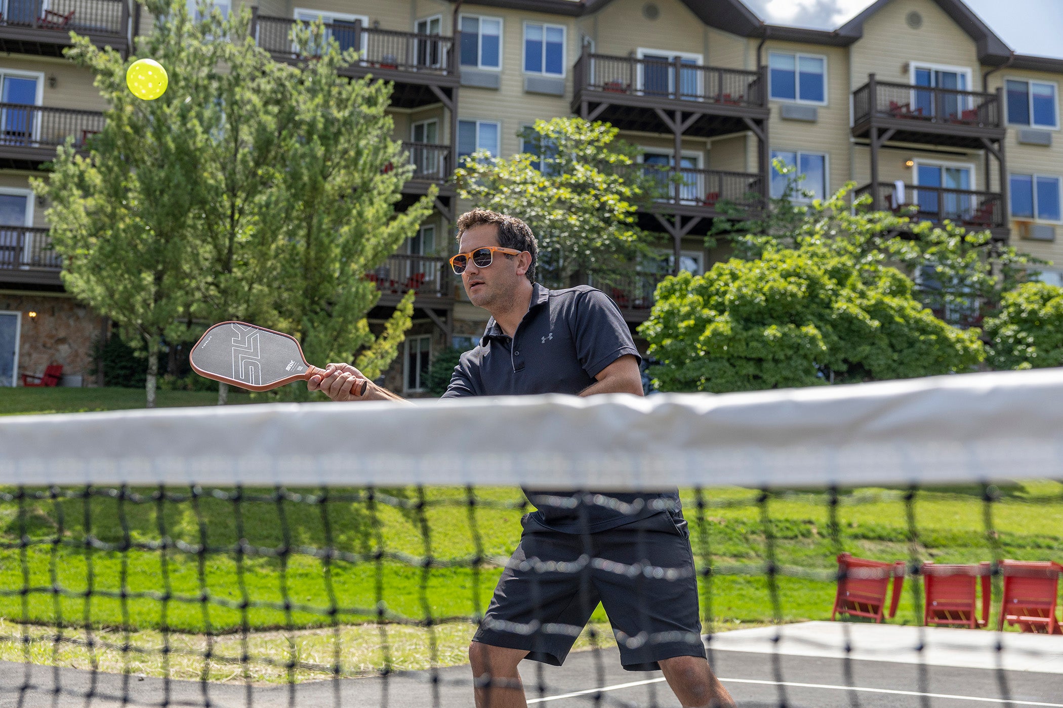 Man hitting ball over pickleball net.