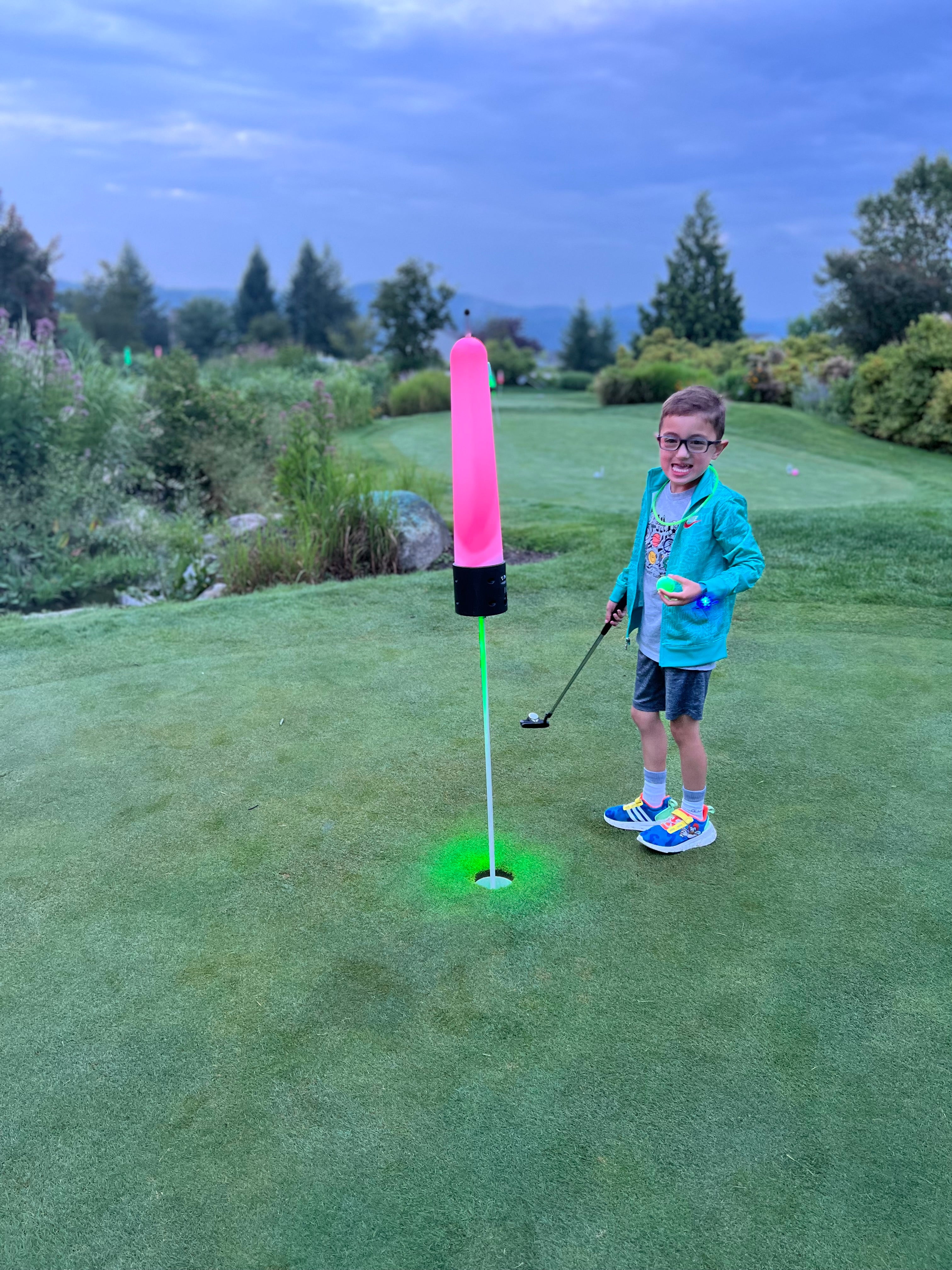 Child playing glow in the dark mini golf.