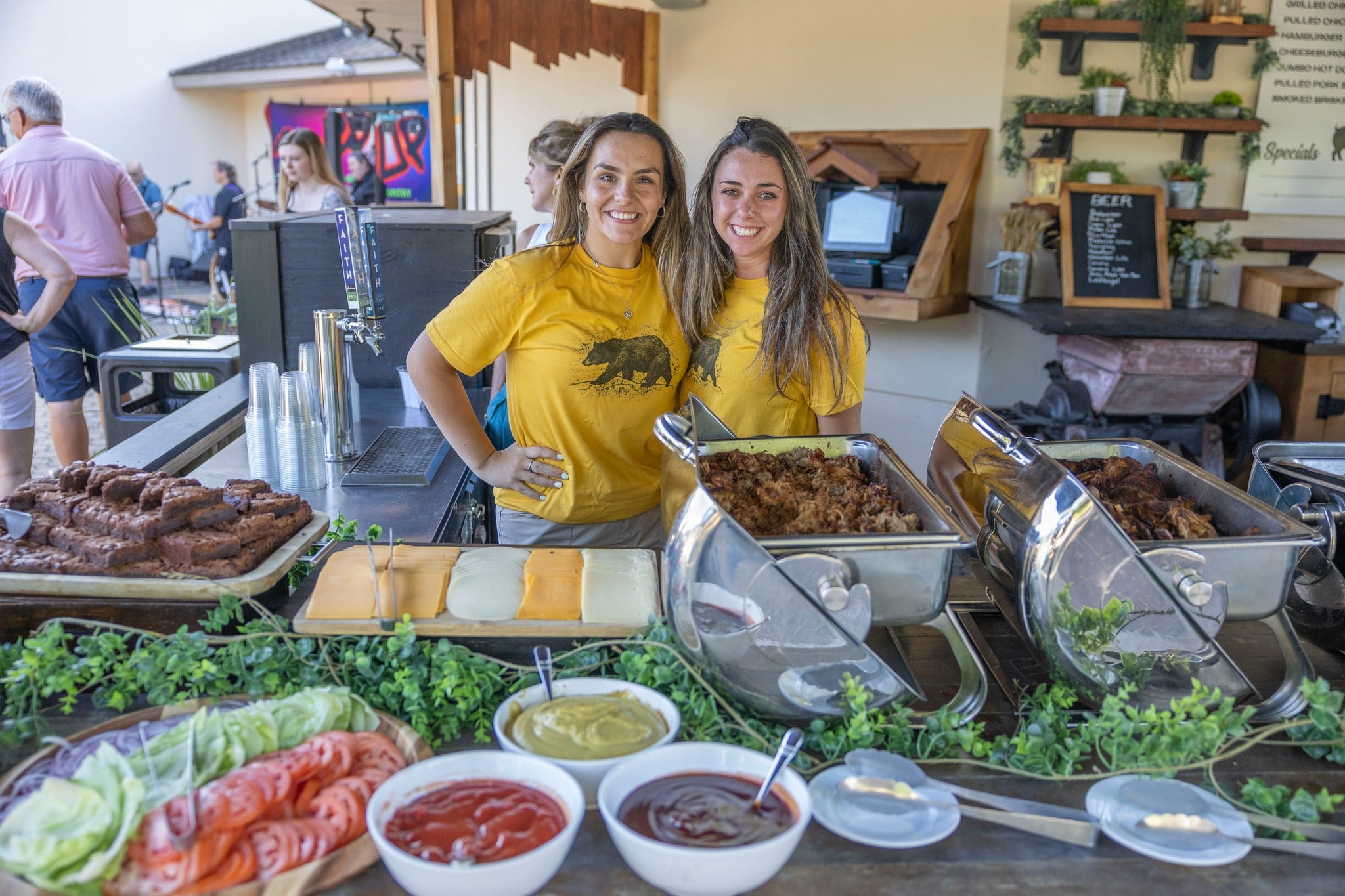 Workers at Black Bear Bourbon and BBQ in front of food display.