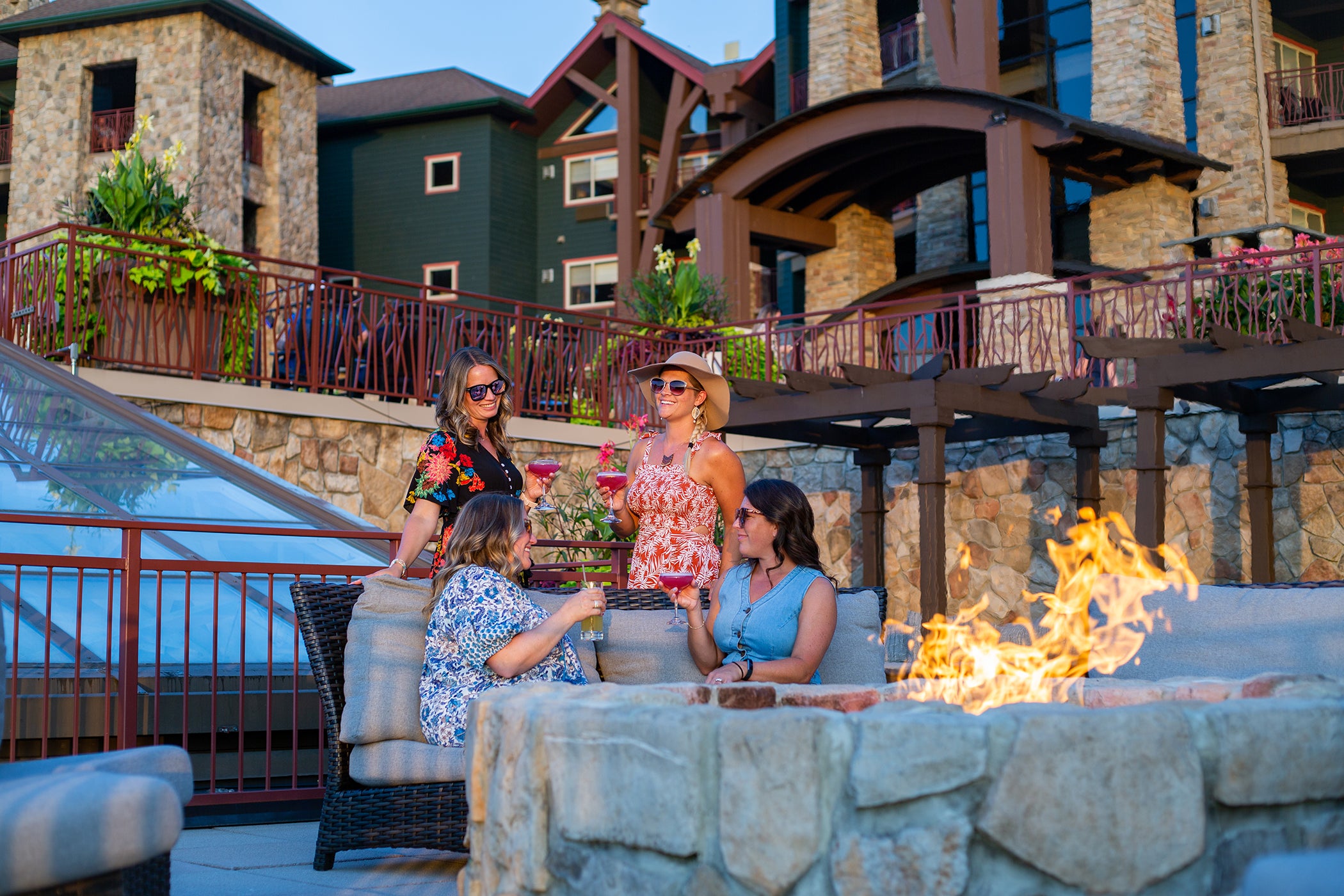 Group of four girlfriends sitting around firepit on Fire &amp; Water terrace.