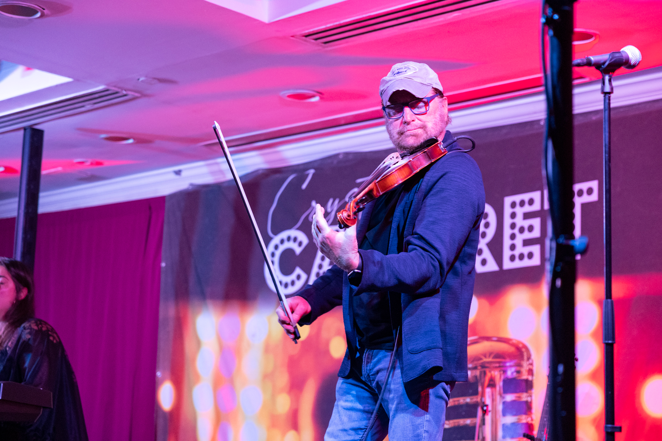 Man playing violin on Crystal Cabaret stage.