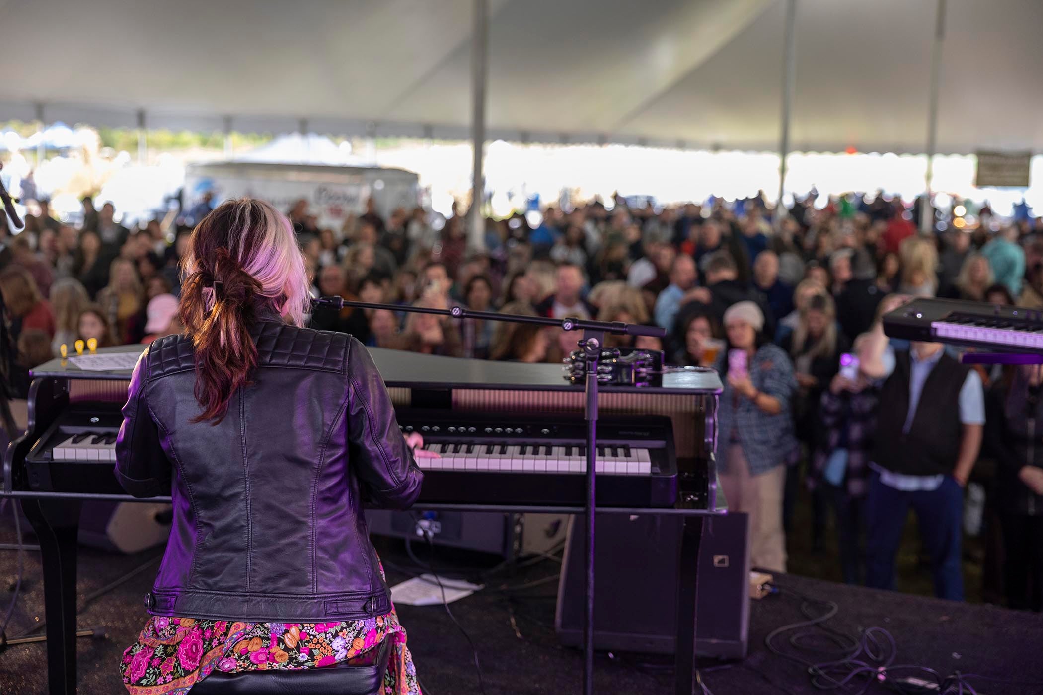 Woman playing the keyboard with music fest crowd in front of her.