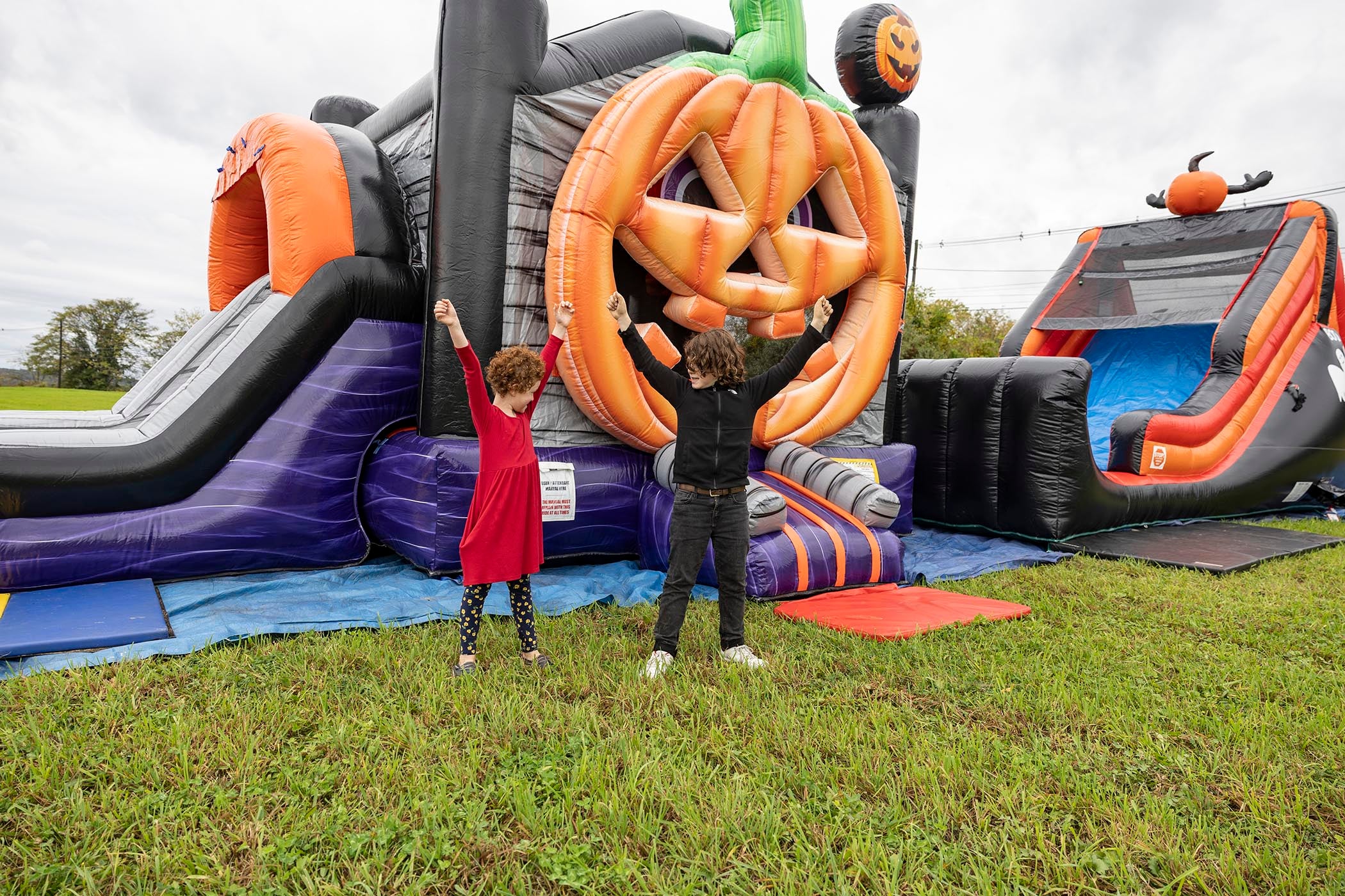 Two children standing in front of halloween themed blow up obstacle course.