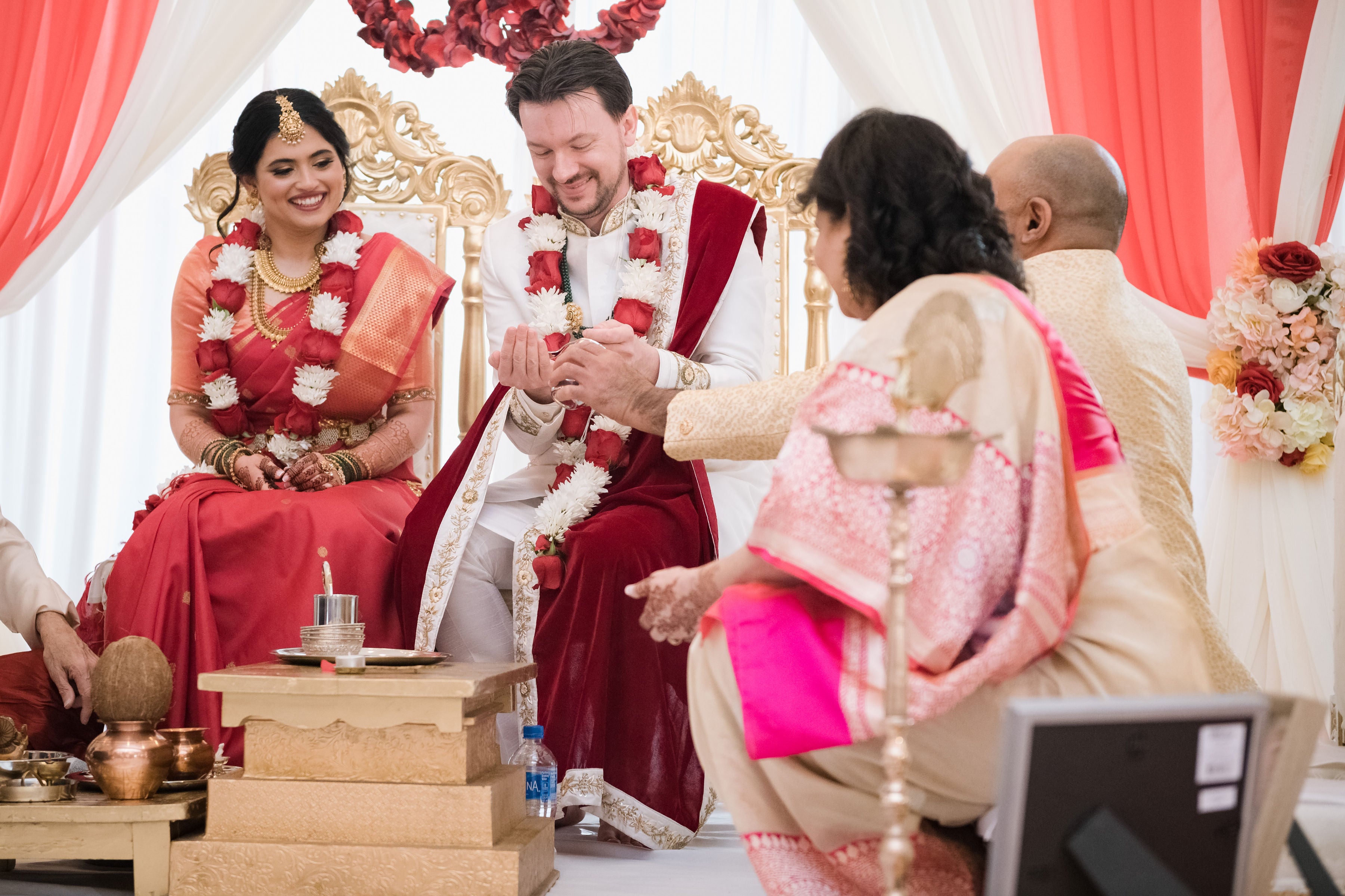 Bride and groom sitting in chairs during their Indian wedding ceremony.