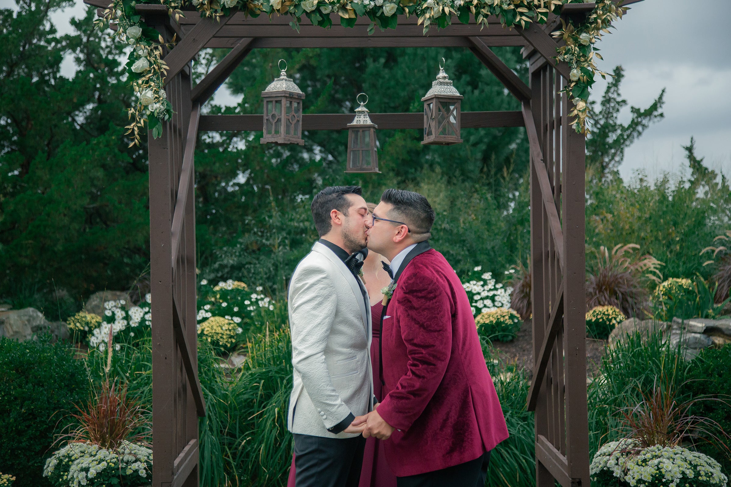 Grooms kissing during their wedding ceremony.