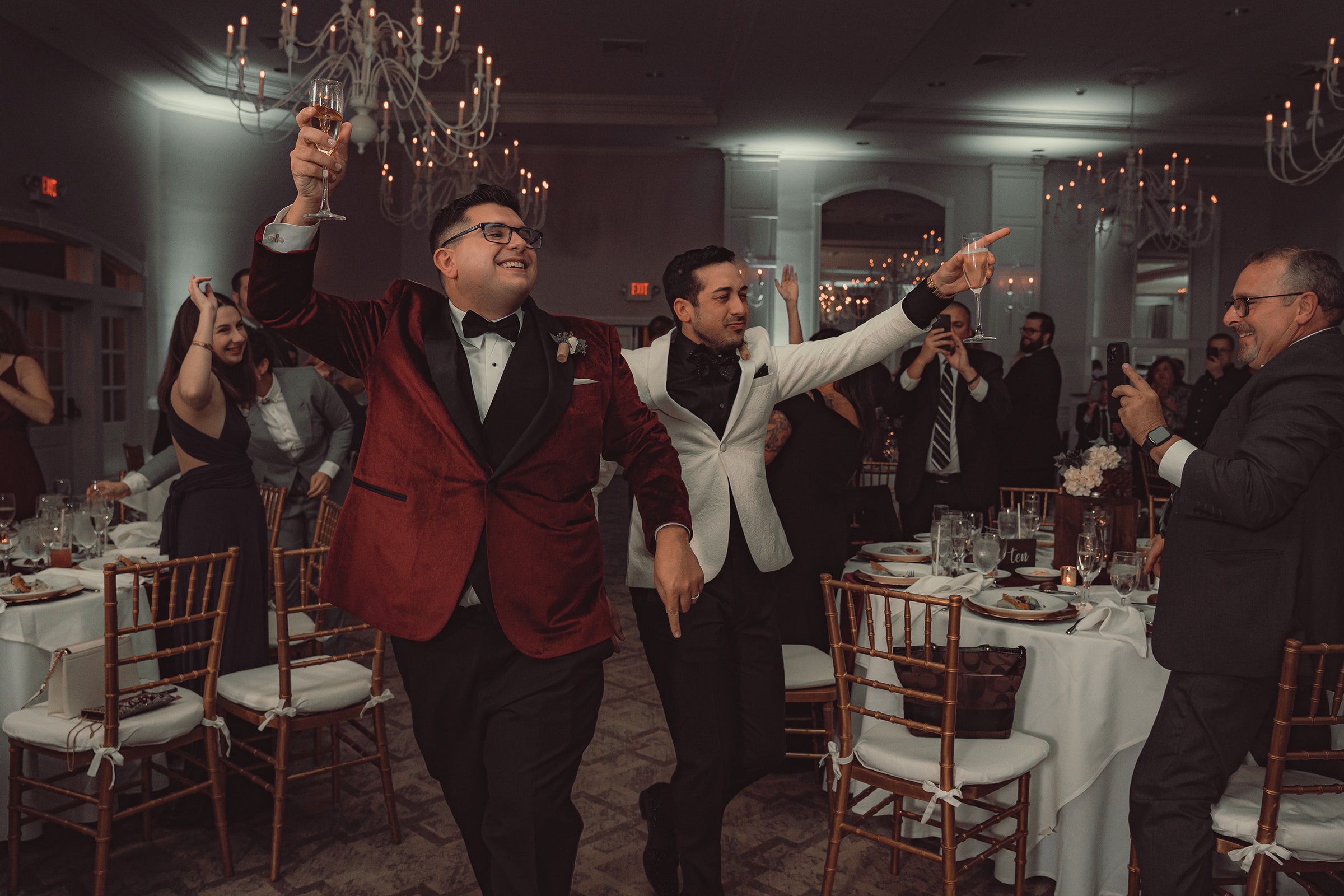 Grooms, holding glasses, making their wedding reception entrance.