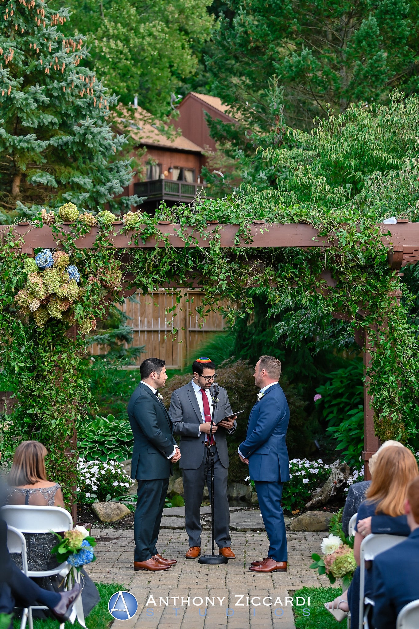 Wedding ceremony for two grooms standing with their officiant.