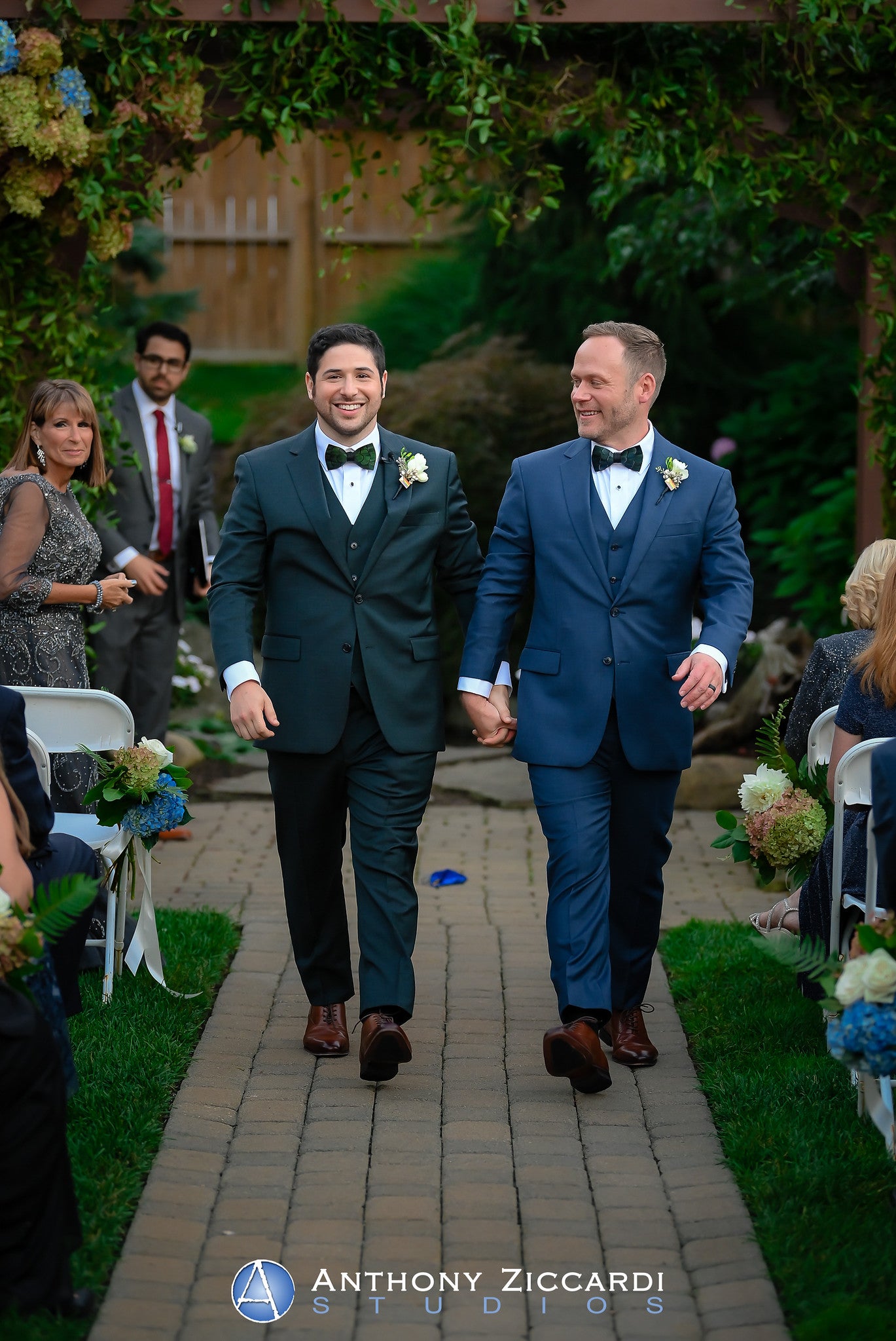 Two grooms, just married, walking hand in hand down the aisle.