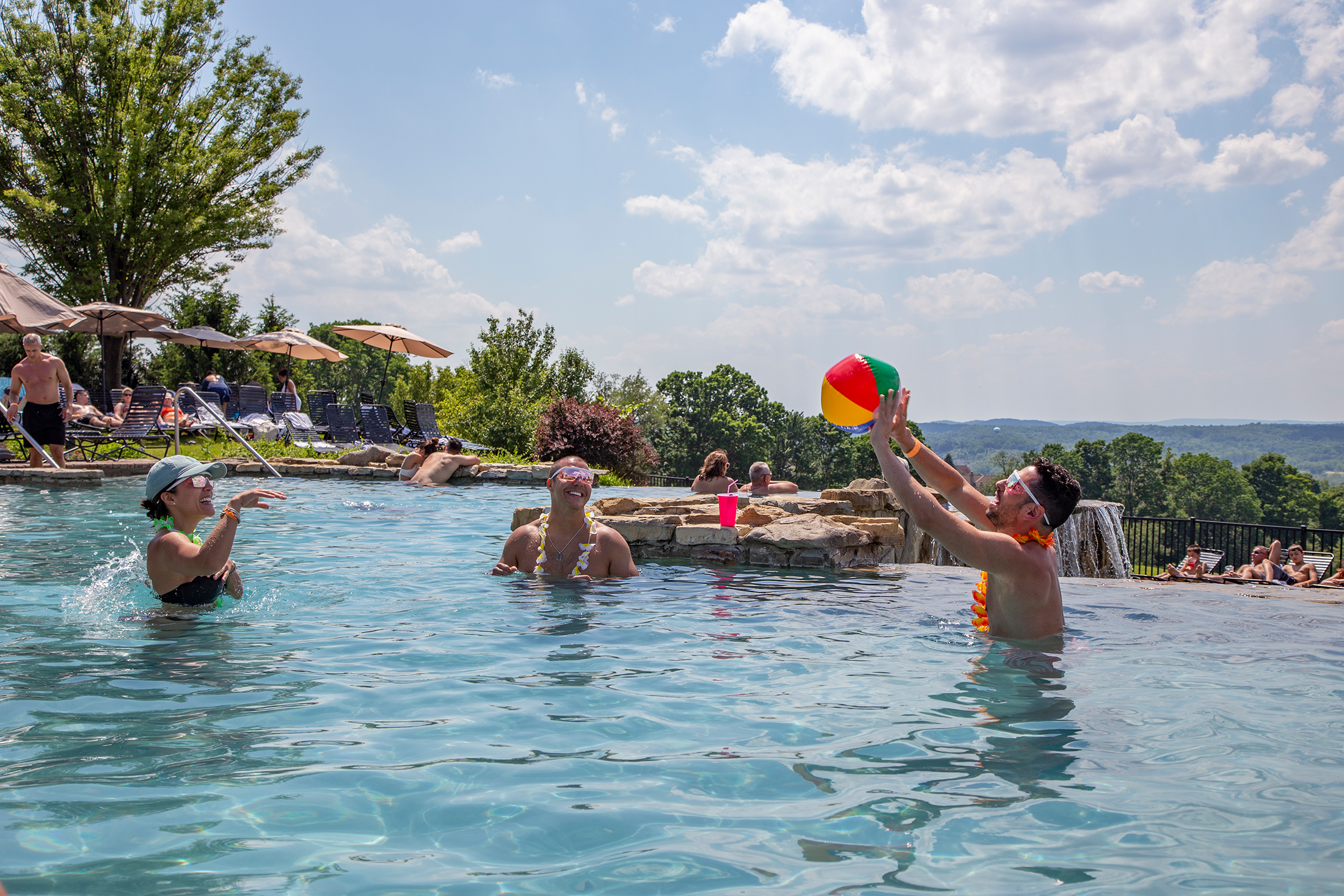 Woman and two men playing with a blow up ball in the Vista 180 pool.