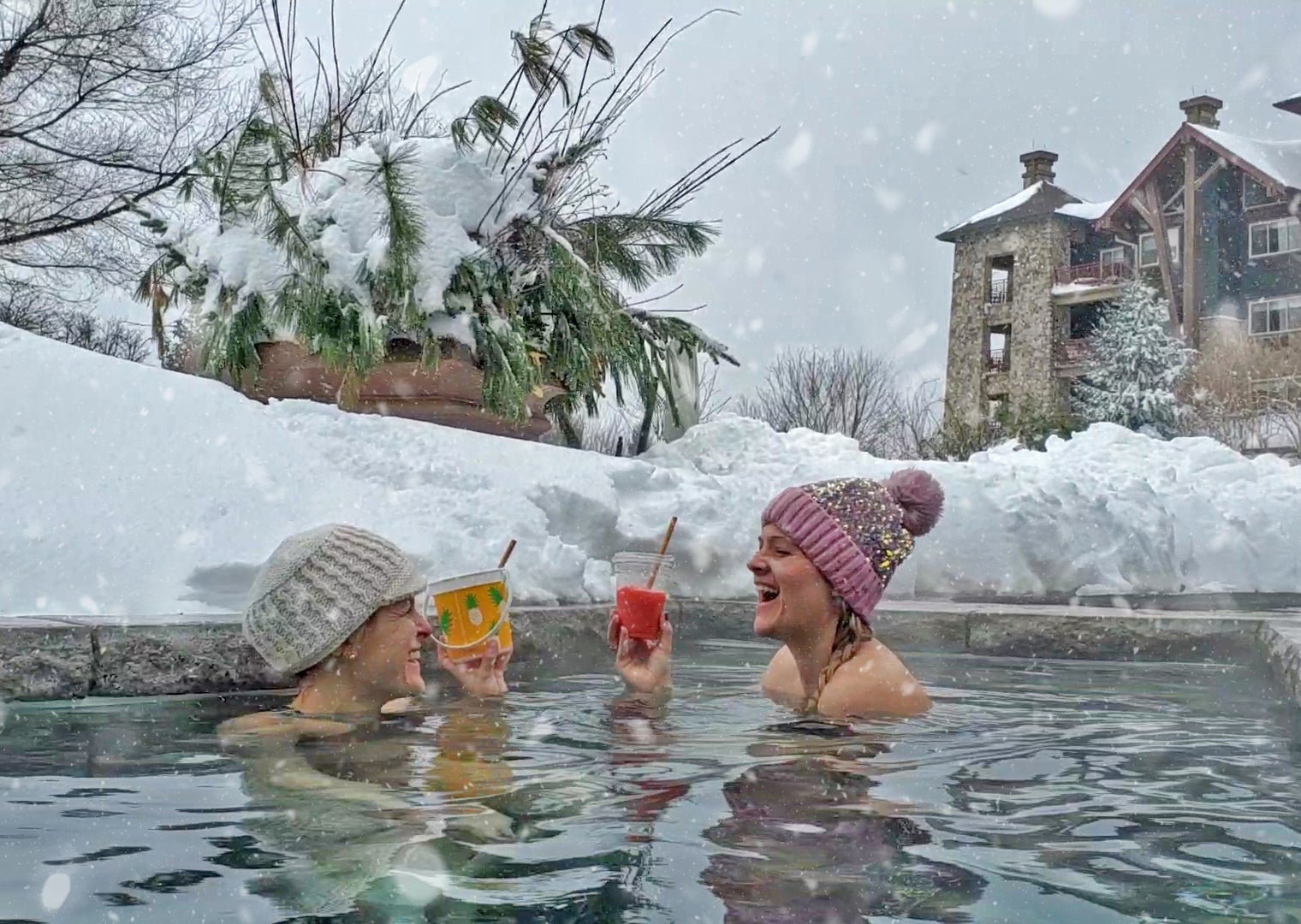 Two women having drinks in the outdoor snow pool at Grand Cascades Lodge.