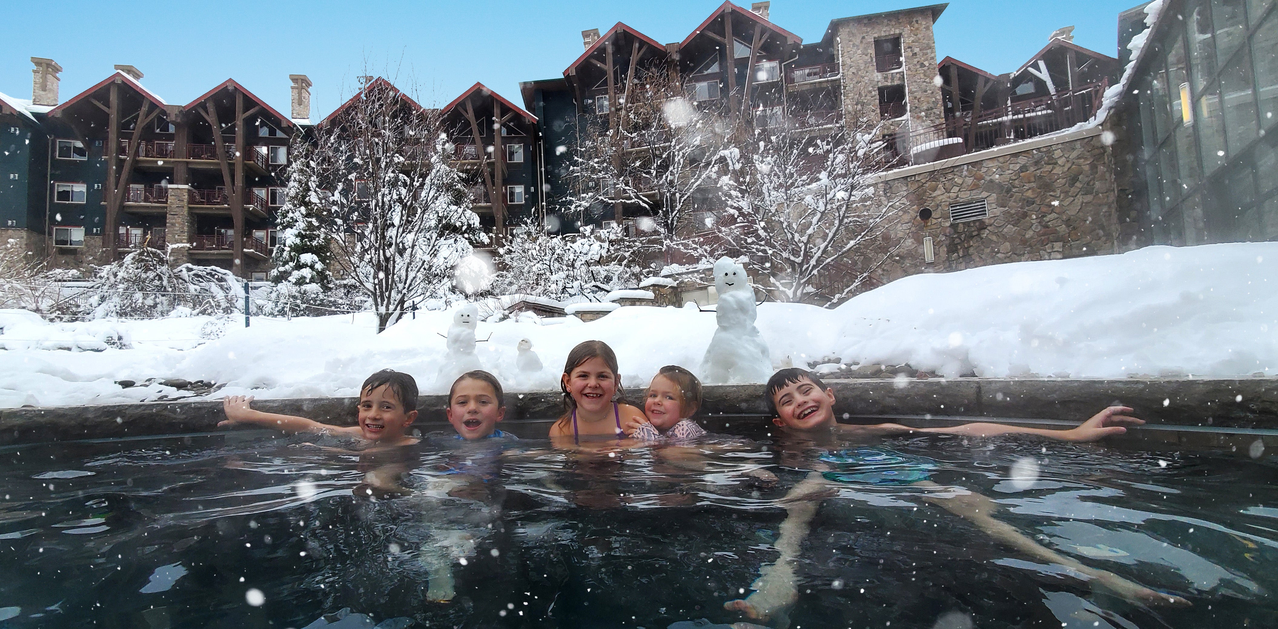 Group of 5 children in outdoor snow pool at Grand Cascades Lodge.
