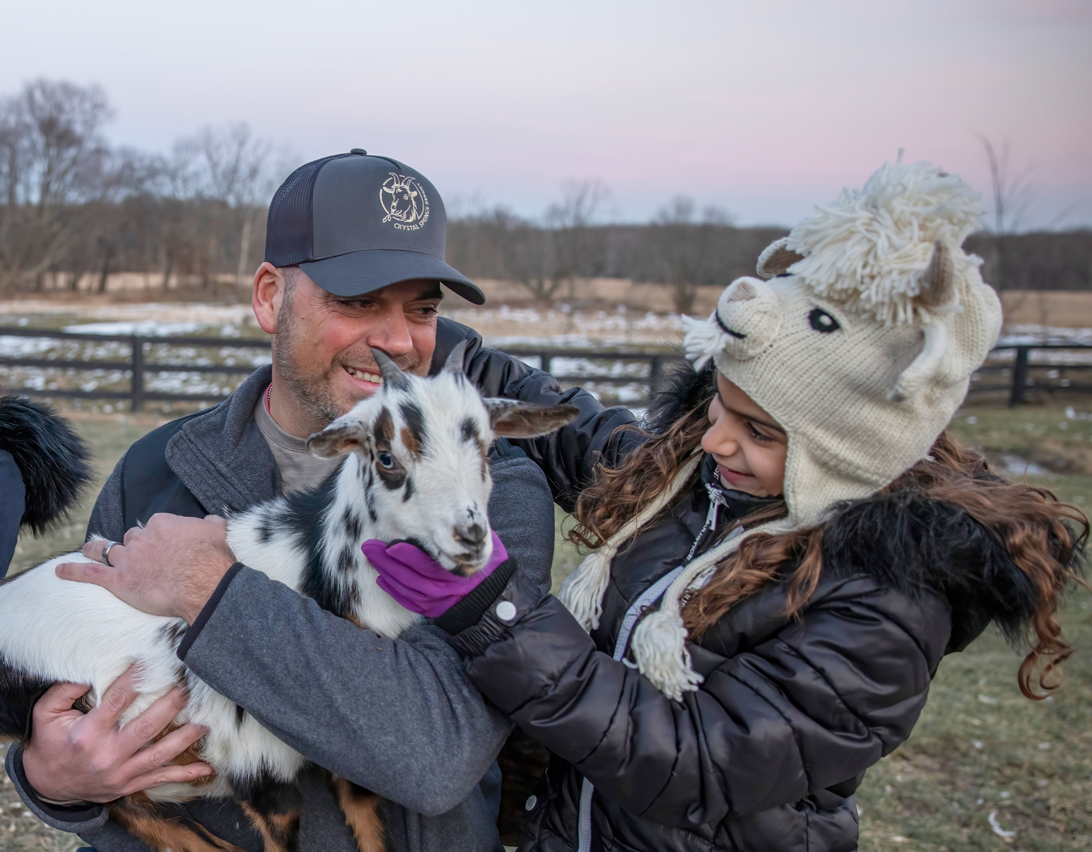 Father and daughter holding baby goat.