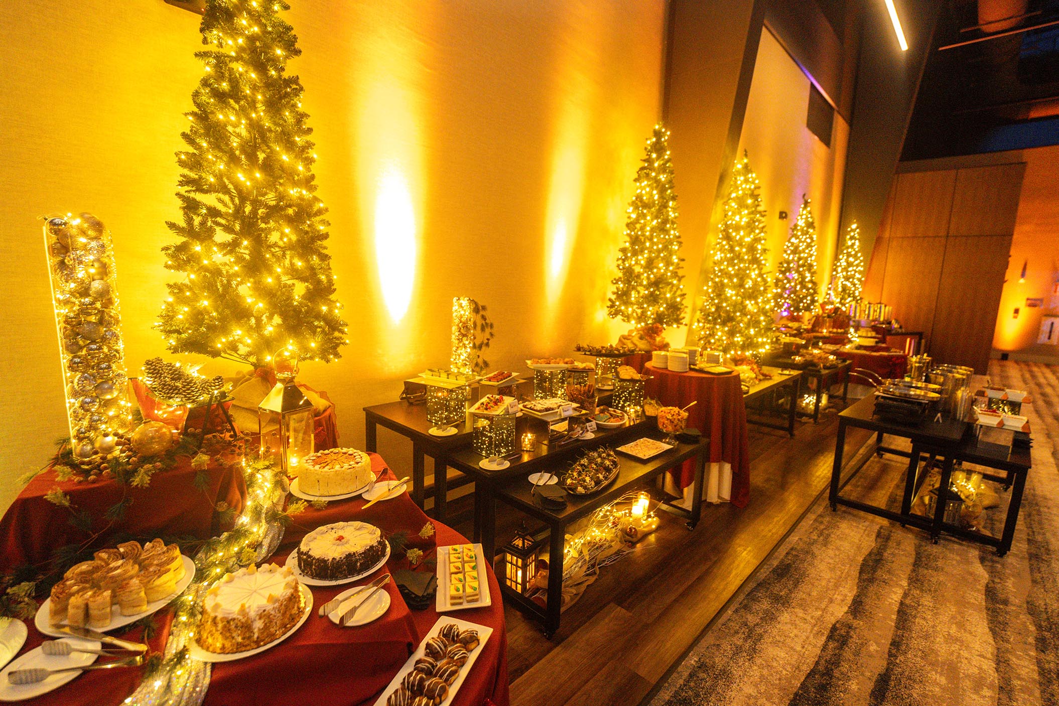 Dessert tables et up in front of Christmas trees during party.