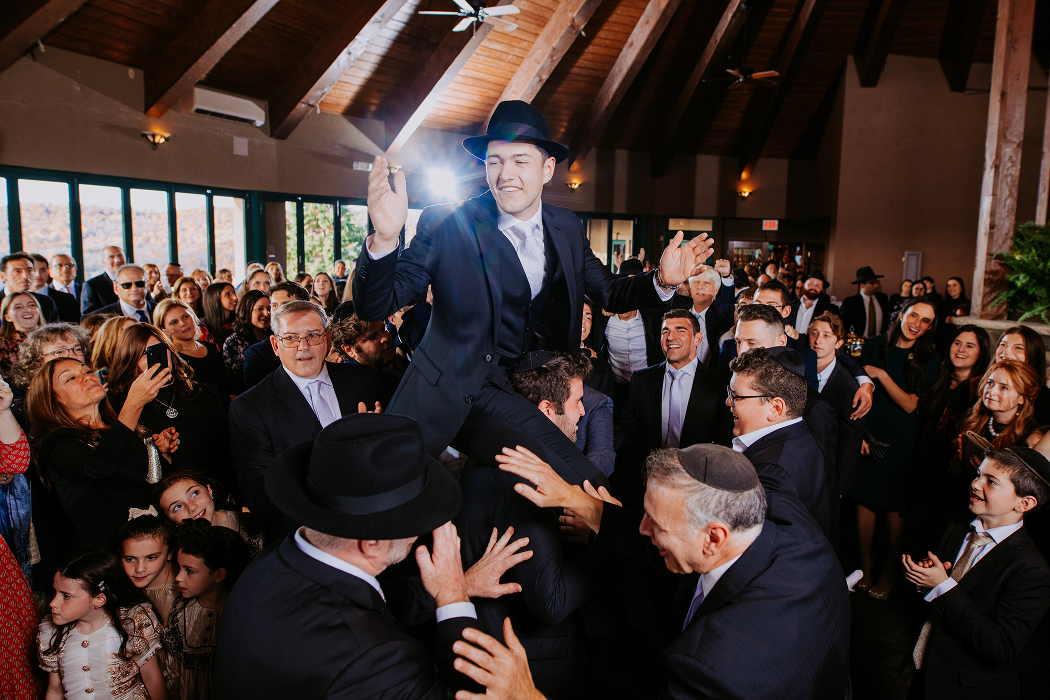 Men holding groom up on their shoulders during wedding ceremony.
