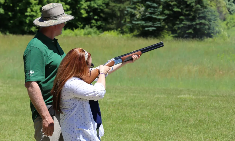 Instructor helping woman shoot laser clays. 