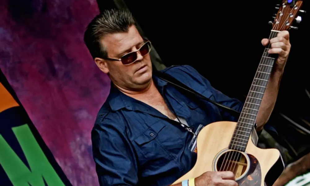 Sean O'Flynn playing guitar on stage. 