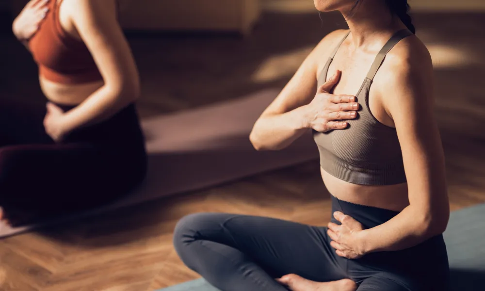 Woman sitting with legs crossed and hands on her chest during yoga. 