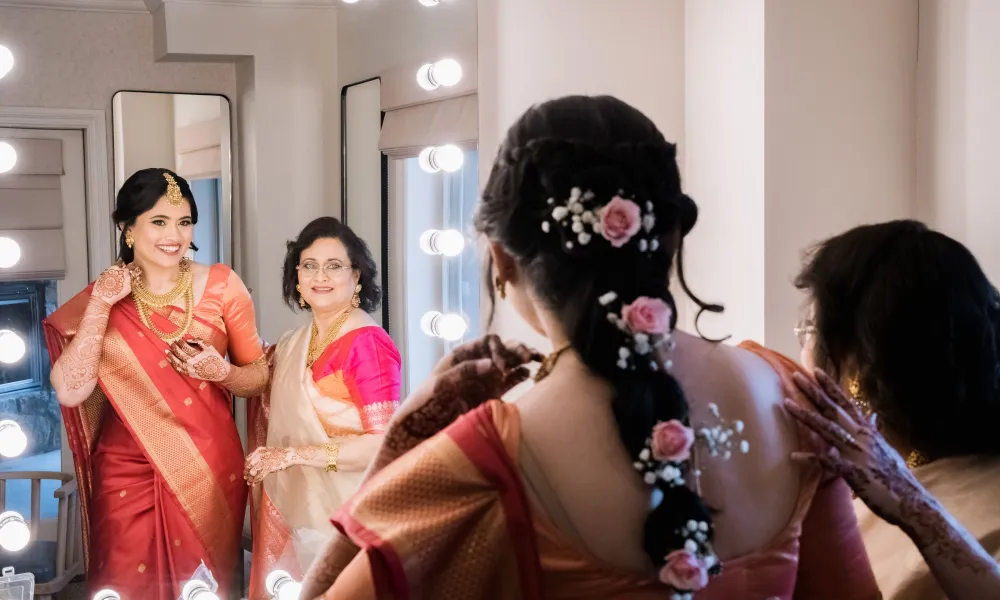 Woman standing in front of lit up mirror on wedding day.