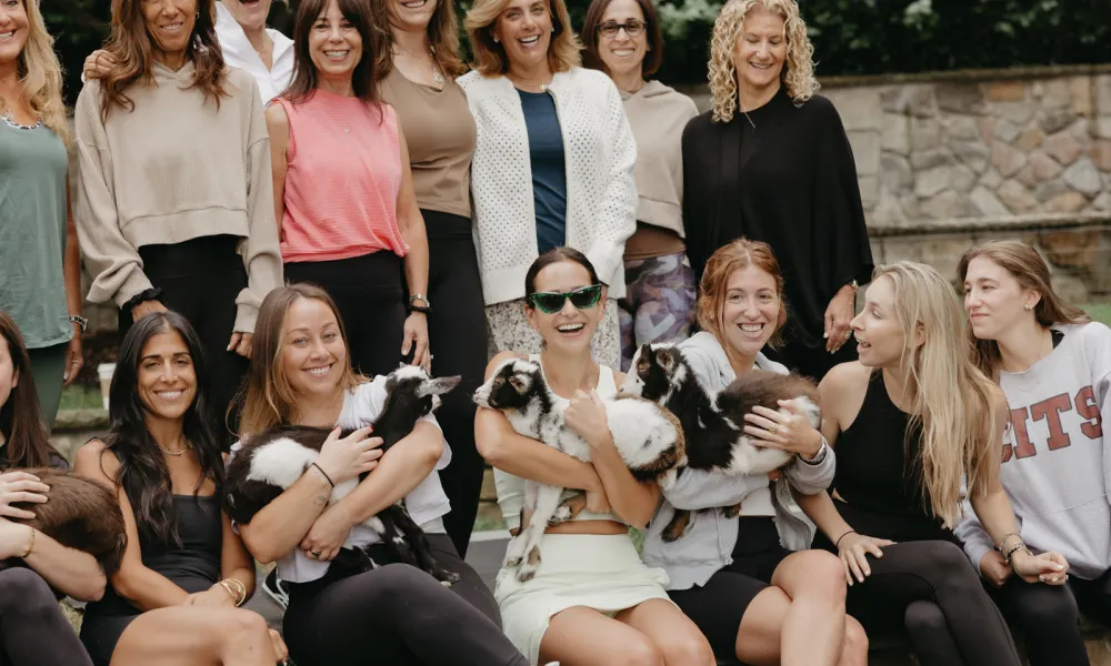 Women holding baby goats.