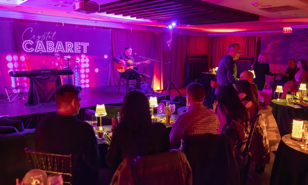 Group of people sitting at a table listening to entertainment at Crystal Cabaret.