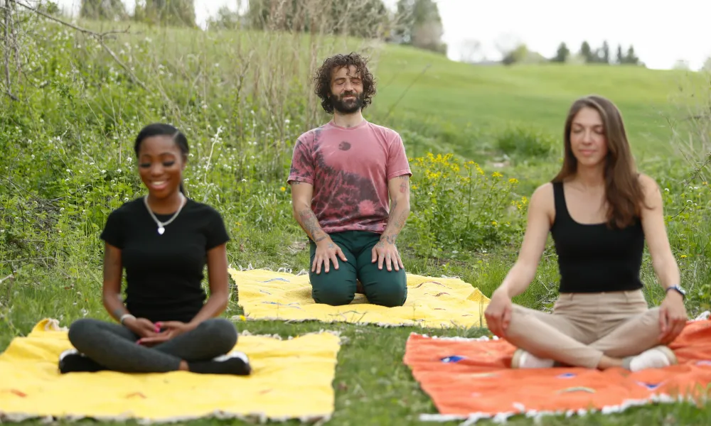 Three people practicing meditation in the forest