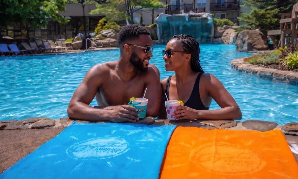 Man and woman holding drink buckets on side of Minerals pool.