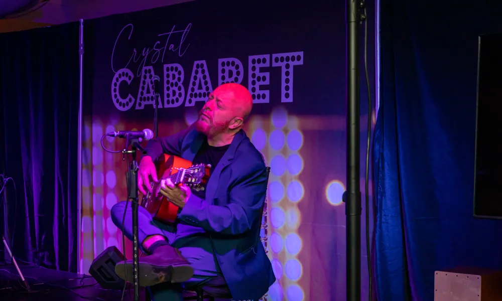 Hernan Romero playing guitar on stage at Crystal Cabaret.