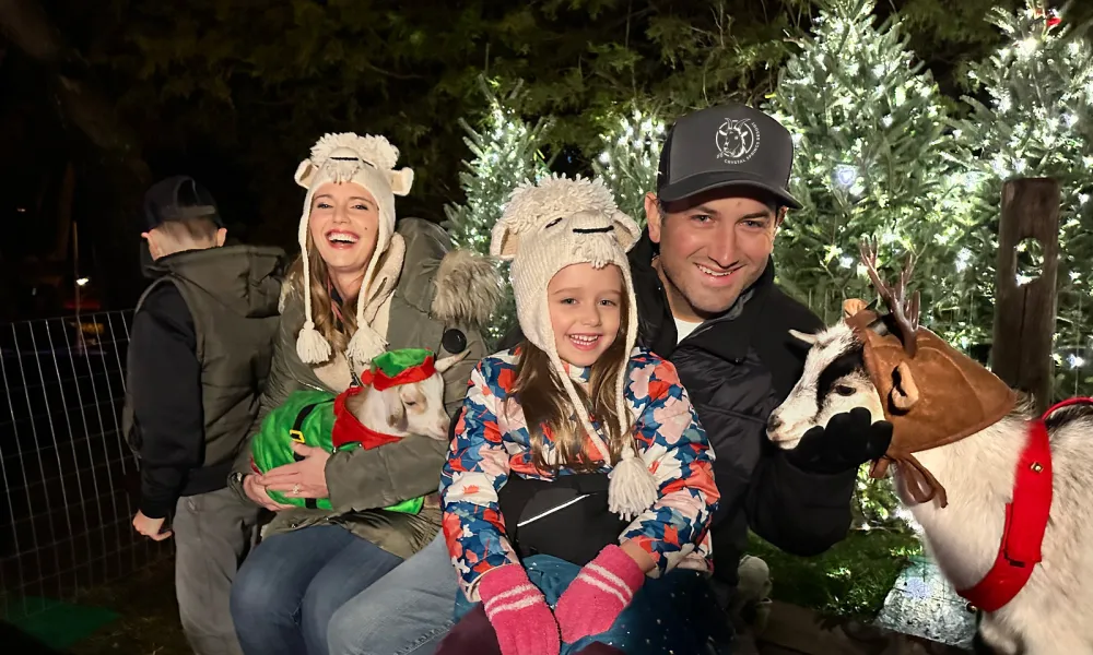 Family of four holding baby goats.