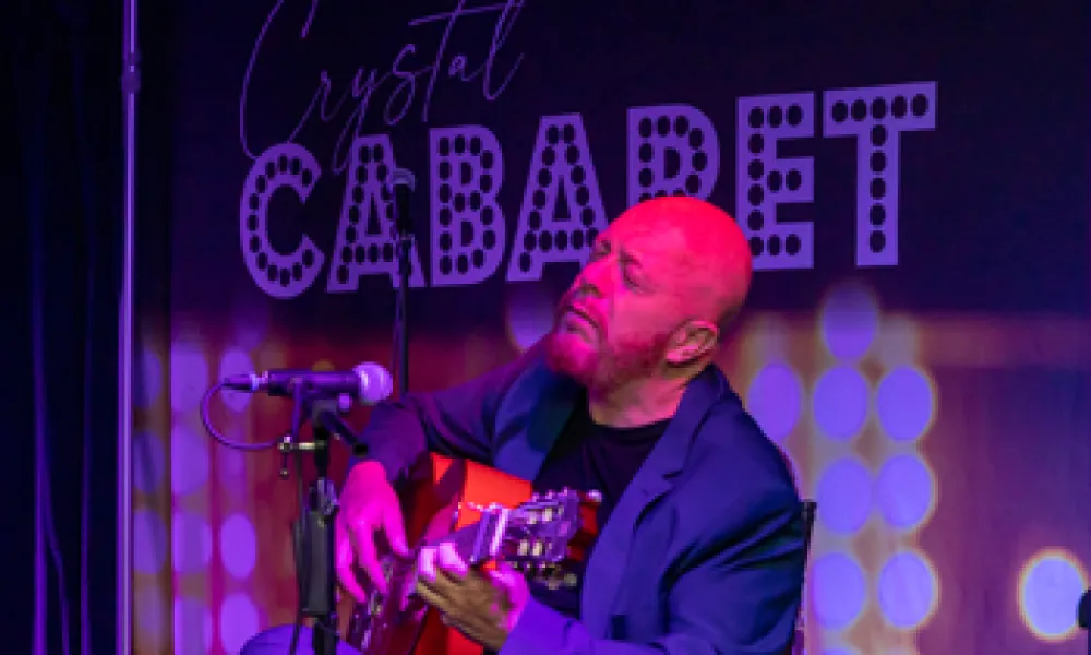 Hernan Romero playing guitar on stage at Crystal Cabaret.
