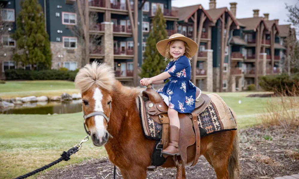 Young girl riding a pony during family vacation.