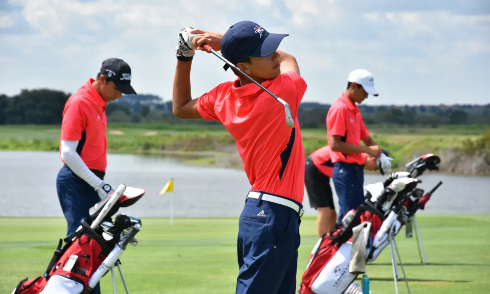 Golfer in orange top swining club at Leadbetter Golf Academy.