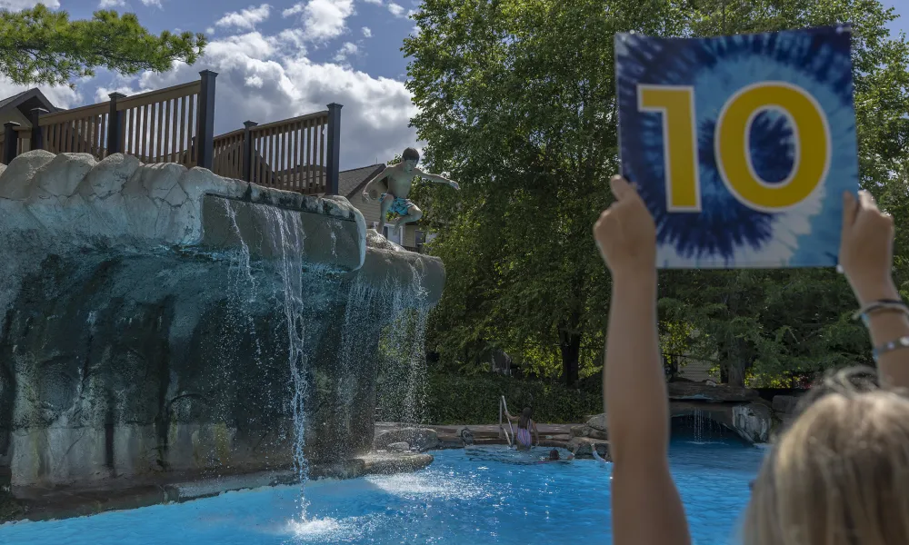 Lifeguard holding tie dyed sign with the number 10 displayed.