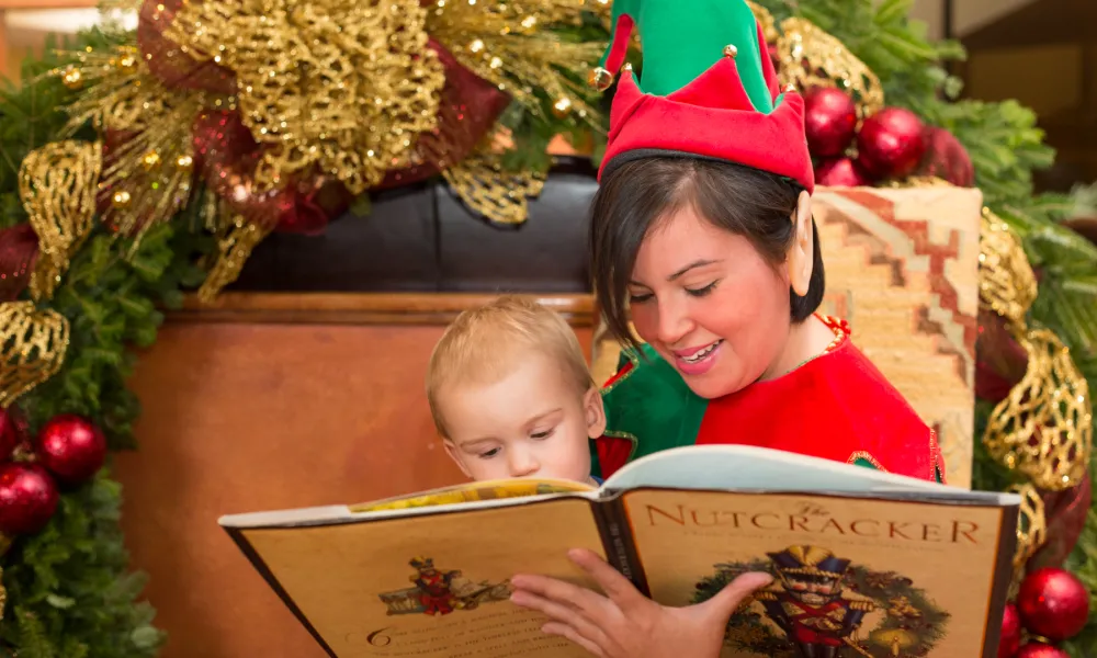 Woman dressed in elf costume reading story to child.