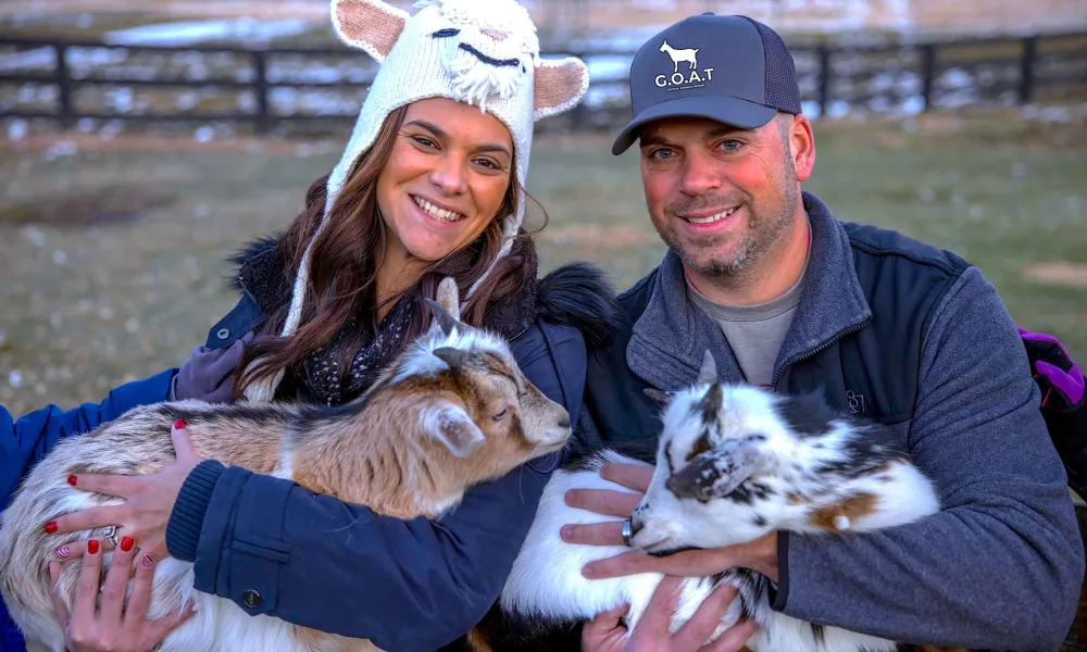 Couple holding baby goats.