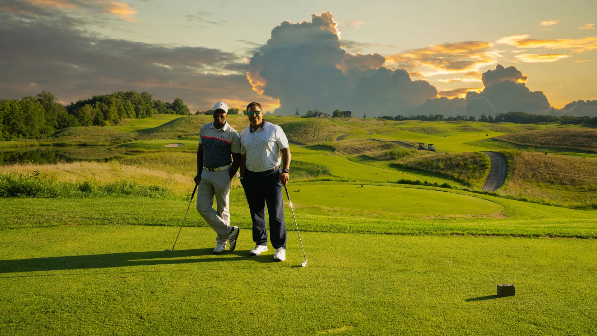 Two golfers stand on Ballyowen Golf Course with sunset behind them. 