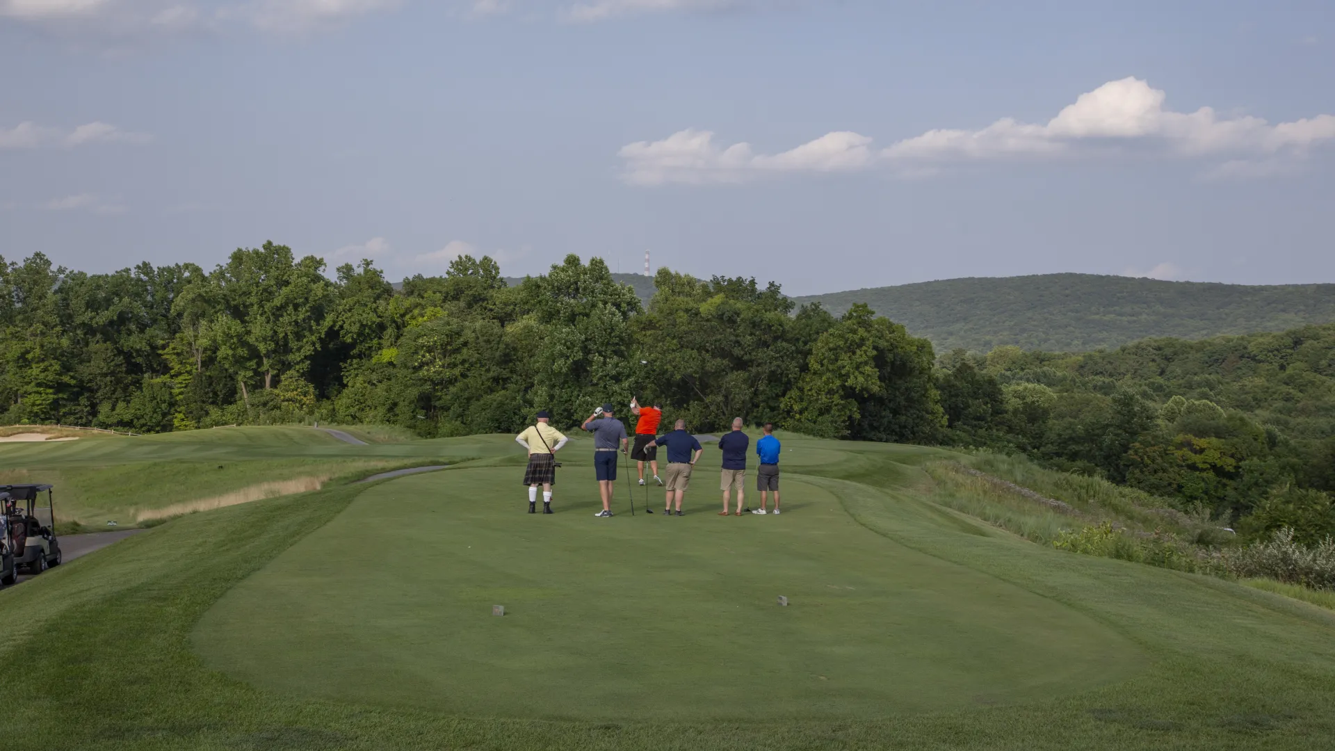 Golfers looking out over tree range. 