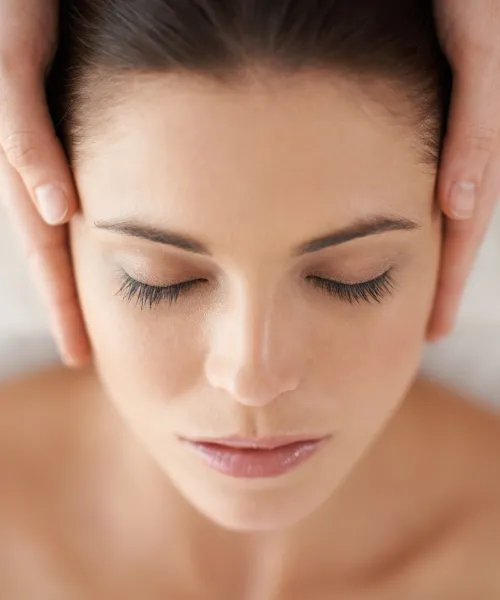 Woman laying down with two hands on either side of her head.