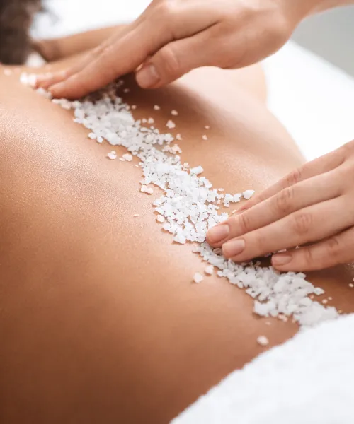 Salt scrub down woman's back during spa treamtment.