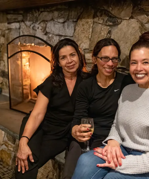 Girlfriends sitting by fireplace.