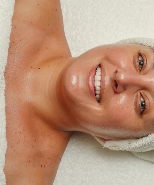Woman laying on table in white hair towel smiling