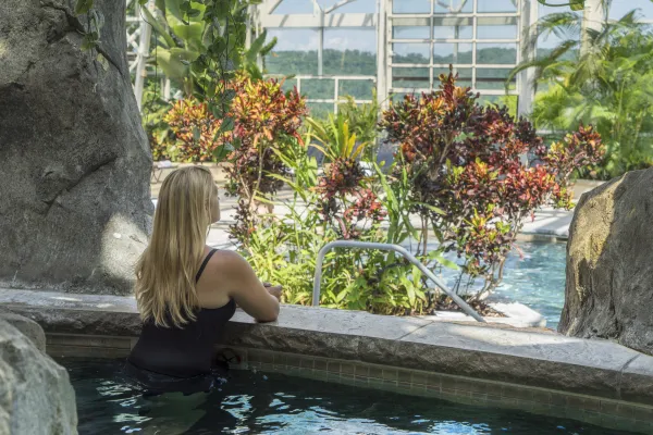 Woman in hot tub at Biosphere Pool Complex looking out over pool.