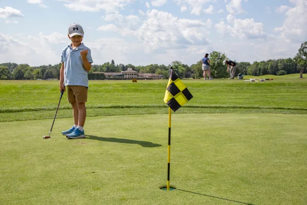 Child standing next to golf flag.