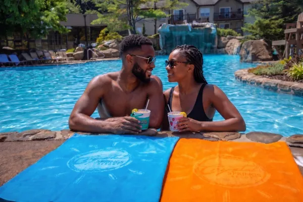 Man and woman holding drink buckets on side of Minerals pool.