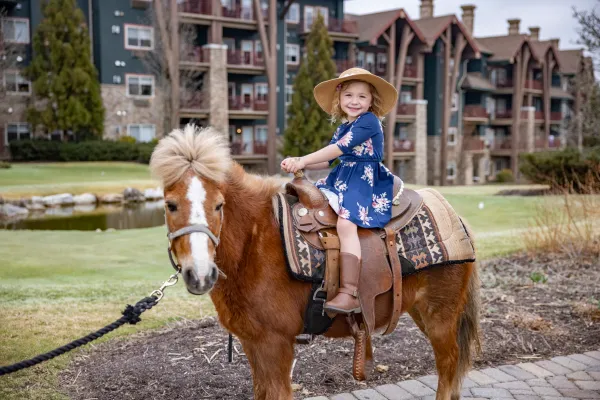 Young girl riding a pony during family vacation.