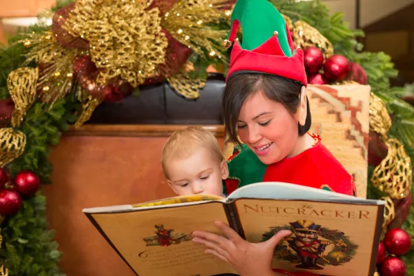 Woman dressed in elf costume reading story to child.