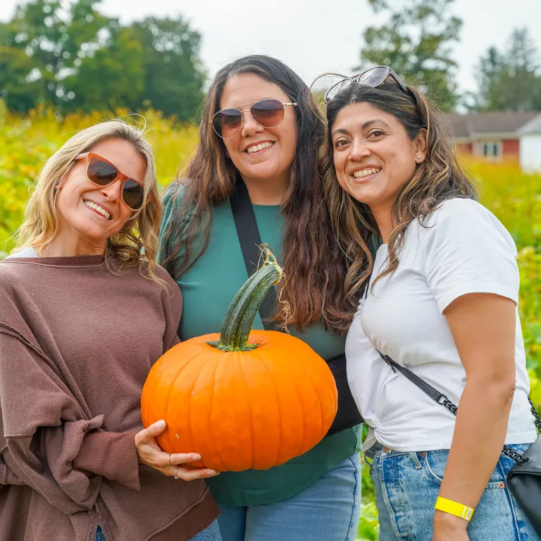 Three girlfriends at pumpkin patch.