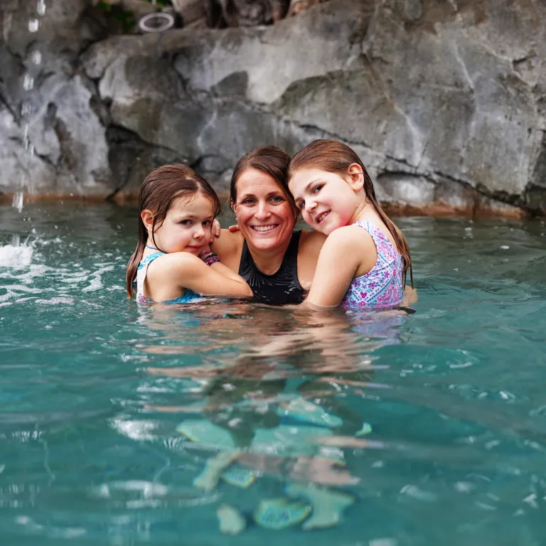 Mother holding her children in pool.